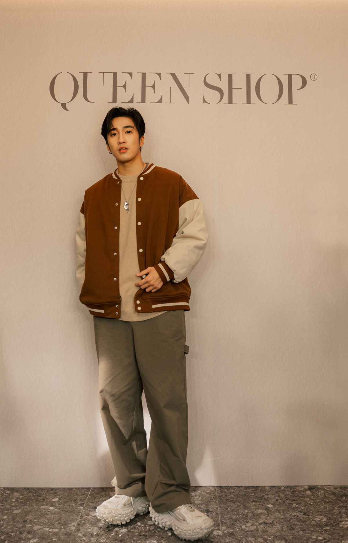 一日店長婁峻碩身穿QUEEN SHOP MEN 系列絨面撞色棒球外套搭配大地色針織毛衣、俐落直筒工裝寬褲，現場演繹陽光暖男