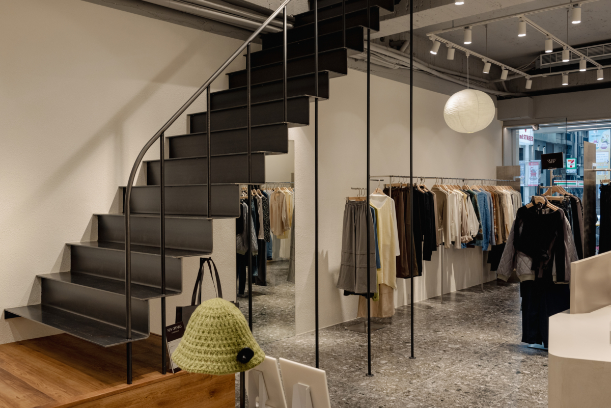 以特殊漆、仿石漆牆面與不鏽鋼展架及生黑鐵樓梯，交織出具有通透感的強烈視覺對比