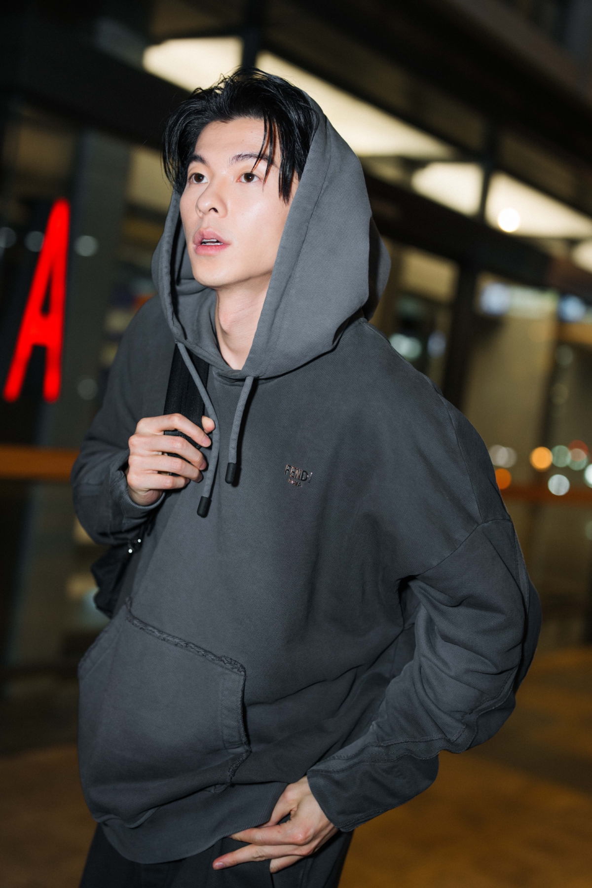 許光漢身穿FENDI 灰色設計帽t搭配深色長褲與黑色休閒鞋,肩背黑色FENDI 後背包