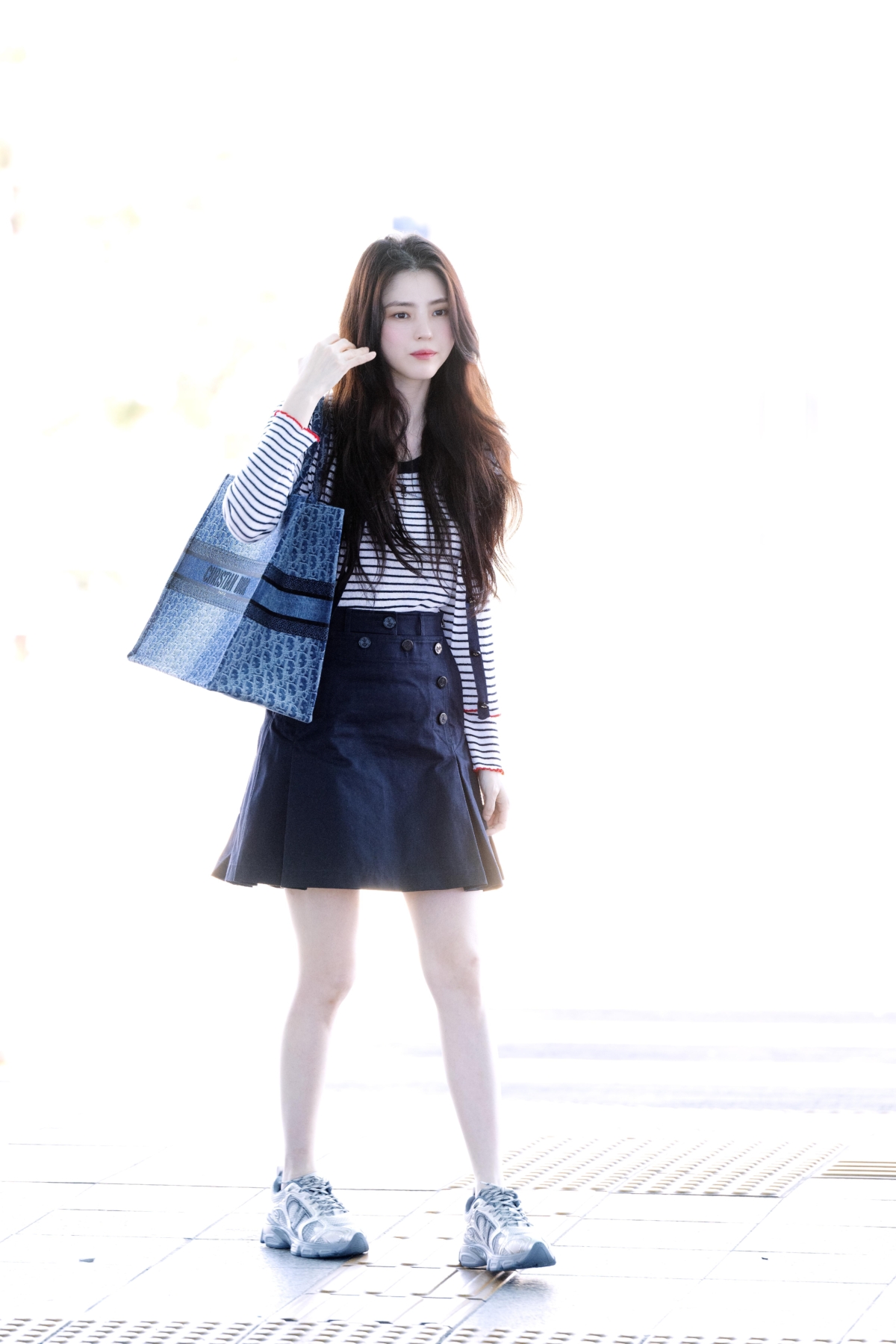 韓韶禧身穿Dioriviera兩件式套裝，搭配水手迷你裙和Dior Chrono運動鞋現身機場，肩上背著Dior Book Tote藍色煙燻Oblique丹寧大型托特包