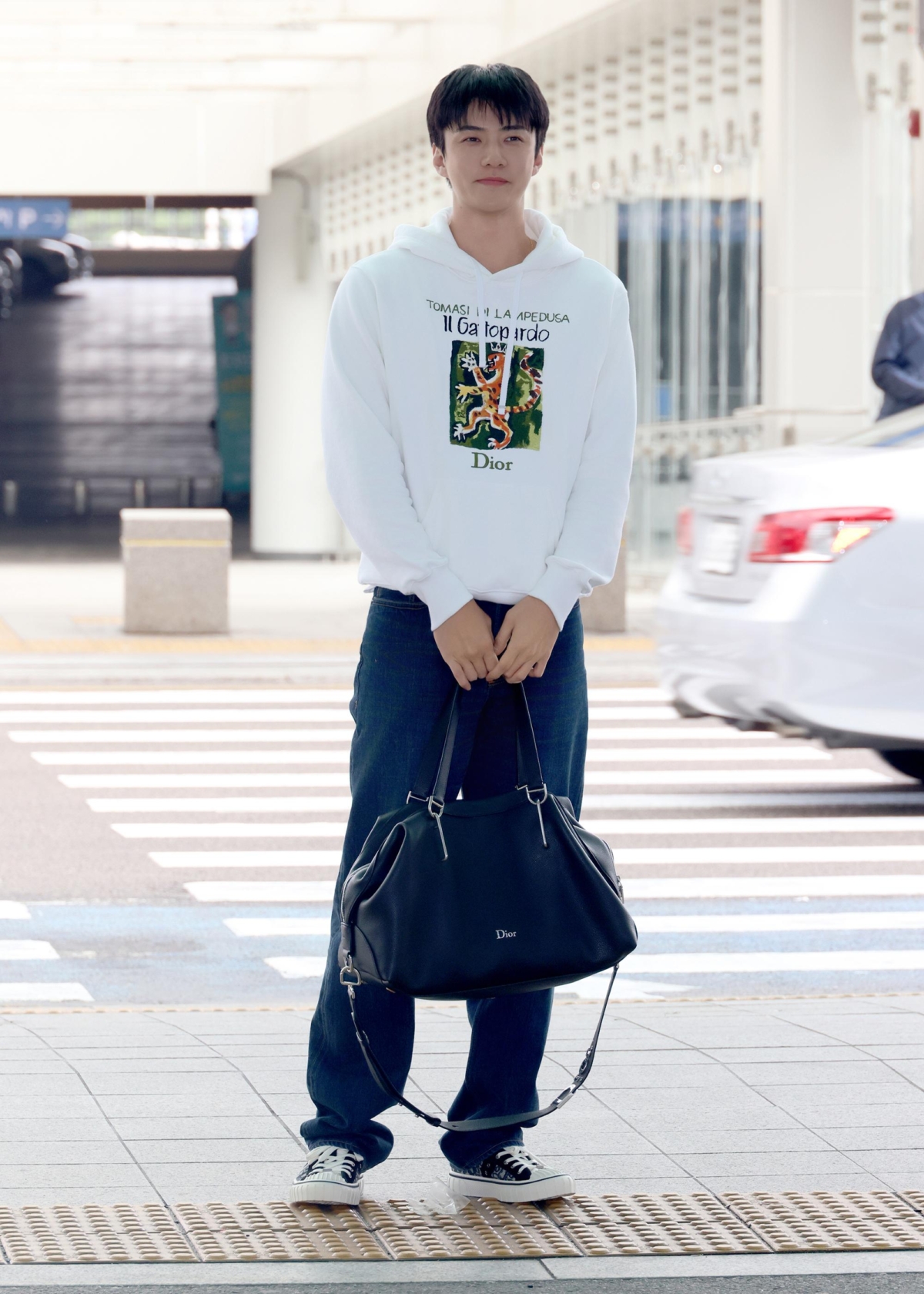 韓國男團EXO成員吳世勳SEHUN穿著Dior Book Cover連帽衫搭配Dior Bolt旅行包與Dior Hooper運動鞋出發前往 Dior 泰國Siam Paragon專賣店開幕活動